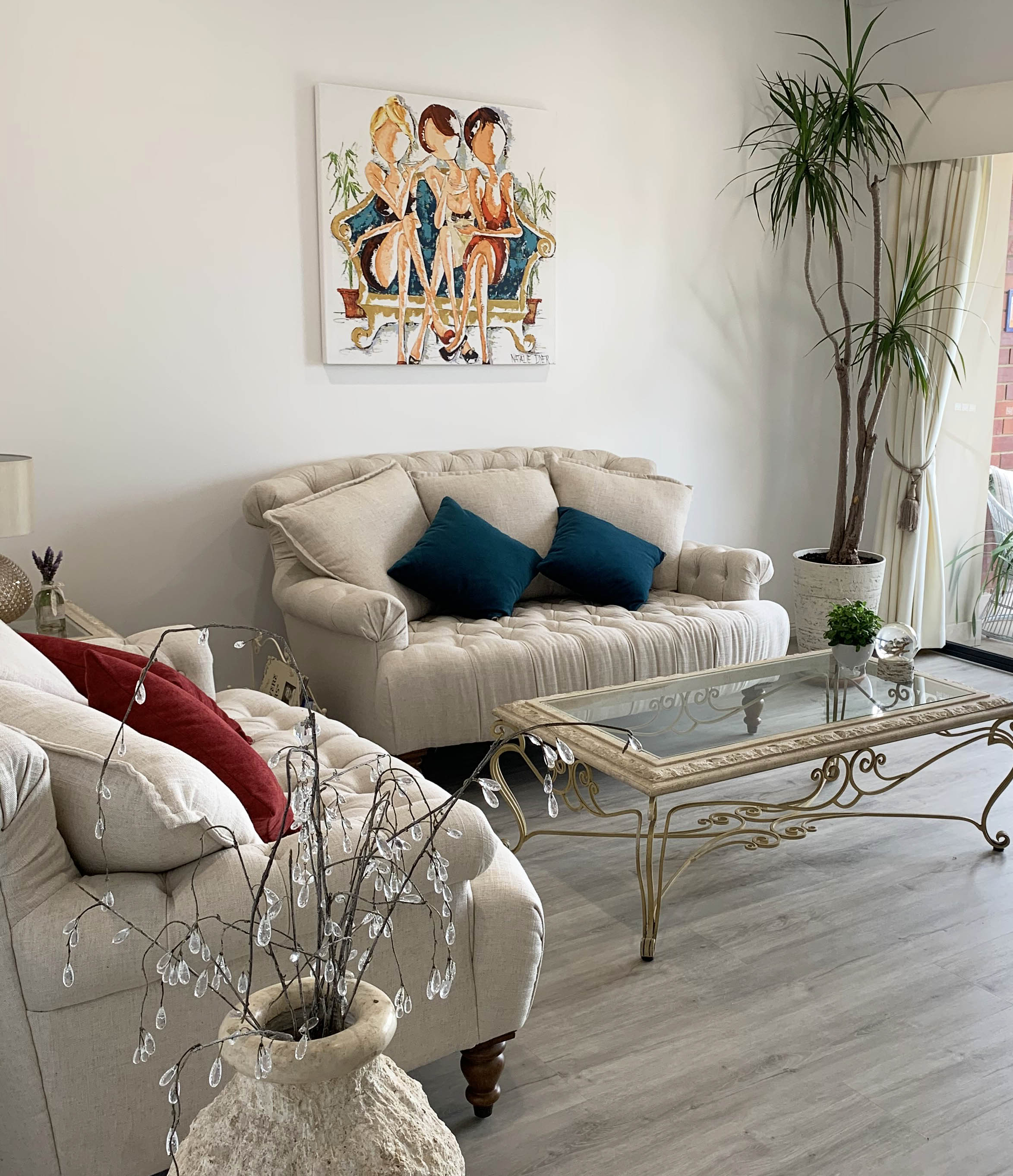 Oh My Goodness hanging in a collector's living room, above a cream buttoned sofa with teal cushions