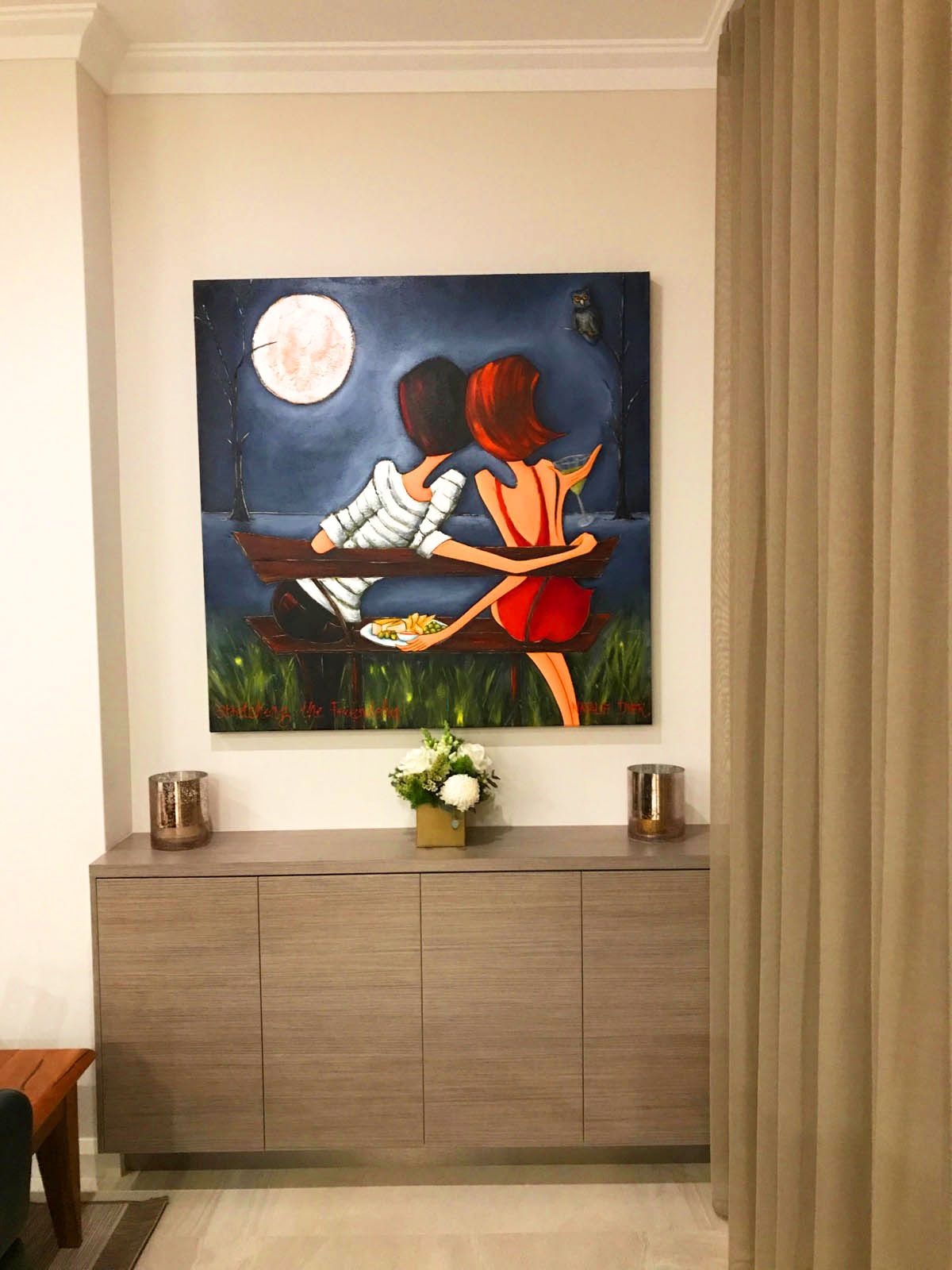 Stretching the Friendship, two friends on a bench under a full moon, hanging above a sideboard in a collector's hallway